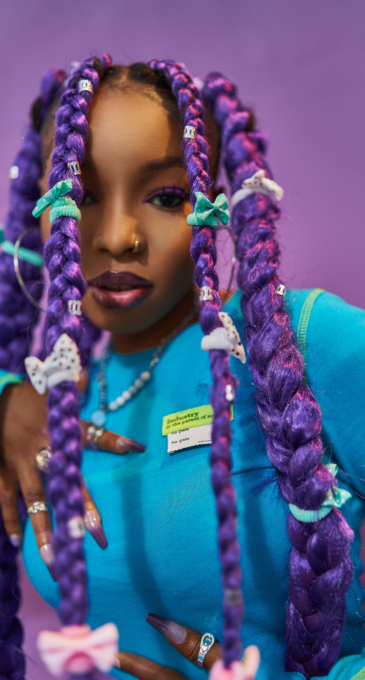 a portrait picture of a popular Nigerian musical artist known as 'Guchi' wearing what looks like a teal tracksuit in a purple background